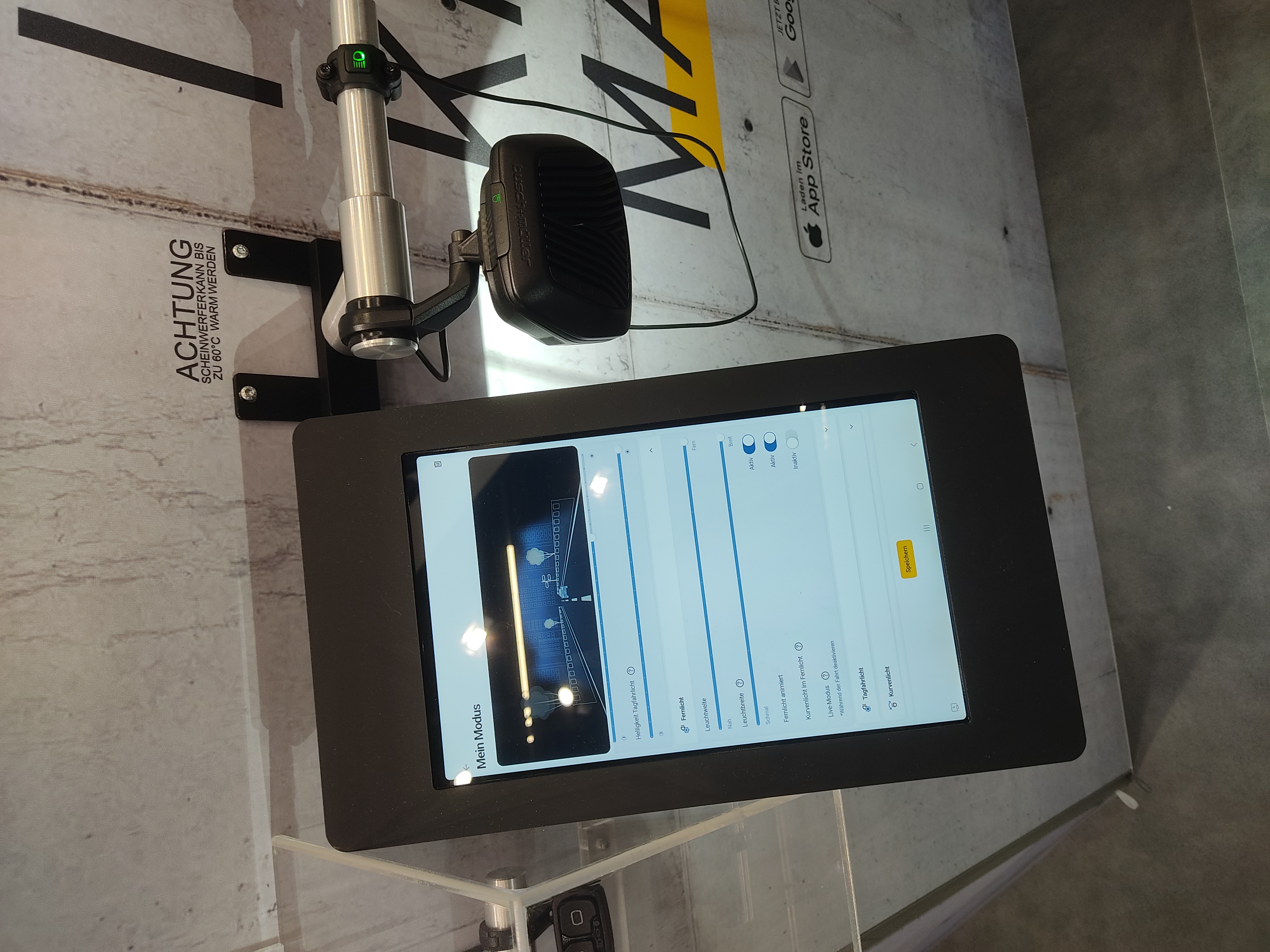A close view of the Briq-XL light, next to it is a tablet detailing the app used to control it